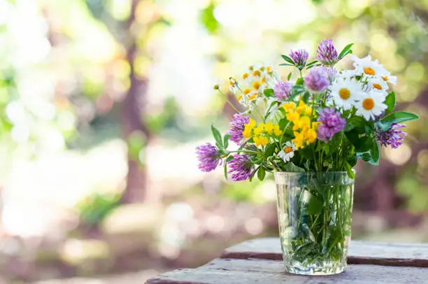Bouquet of wildflowers on the wood table in the blurred nature background