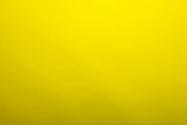 istock Yellow background made of real colored paper, illuminated by a soft light from above. 1253340008