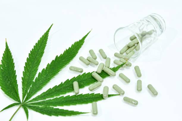 cannabis leaf and pill capsules are in the glass - photography sign table ganja imagens e fotografias de stock