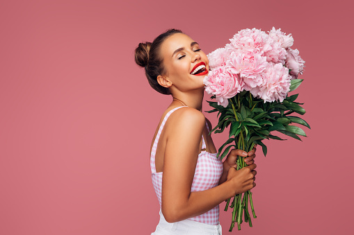 Happy young woman holding bouquet of pink flowers