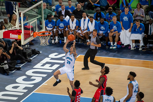 Elevated view of basketball player in white jersey aiming hoop during the match.