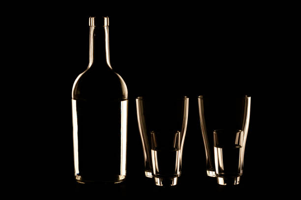 bottle and piles on a black background a glowing contour. abstract glassware for drinking
