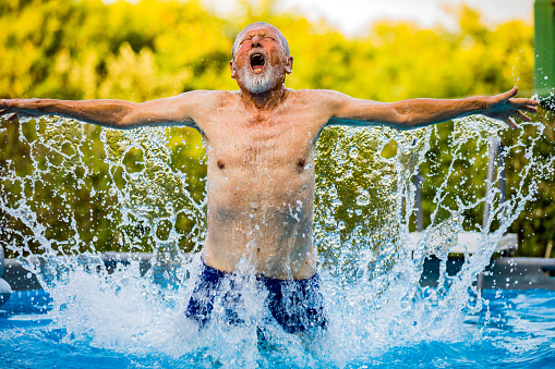 Healthy senior man swimming in the pool. Happy pensioner enjoying sportive lifestyle. Active retirement concept.