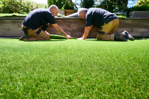 Two workers making sure artificial grass fits properly