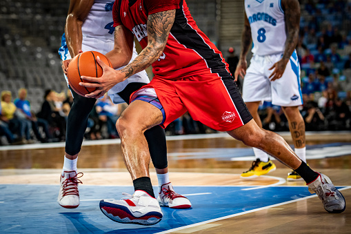 Low section of basketball players tackling for ball during the match.