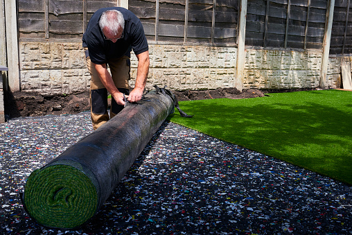 Worker Installing artificial grass in modern garden of home
