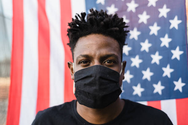 istock Covid-19: Man wearing protective mask with USA flag in the background 1253353652