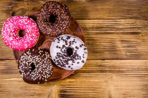 istock Plate with glazed donuts on a wooden table. Top view 1253361981