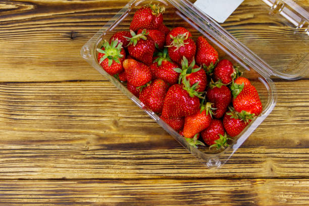 istock Fresh strawberry in plastic box on a wooden table. Top view 1253365611