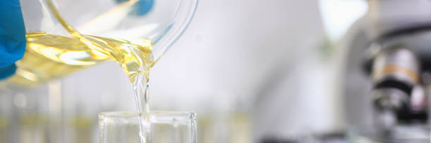 istock Scientist hand wearing protective gloves pouring some yellow liquid at laboratory 1253368926