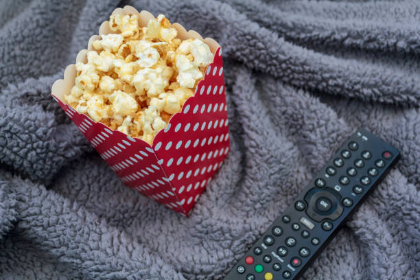 popcorn box and tv remote control on fluffy blanket - remote television movie box imagens e fotografias de stock