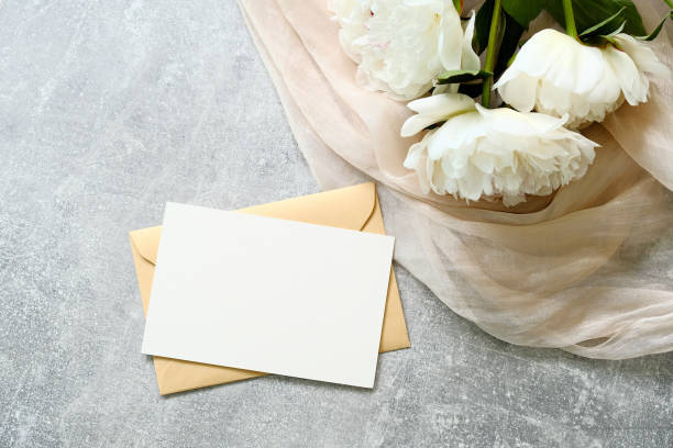 istock Blank paper note with envelope and peony flowers on stone background. Flat lay, top view. Love letter, greeting card mockup for Mother's Day or Woman's Day, wedding celebration. 1253373799