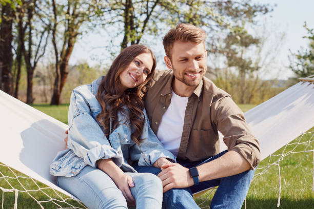 istock Happy man and woman sitting on a hammock 1253374963