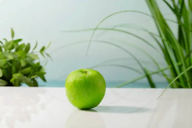 Photo of a delicious looking green apple on a table on an out of focus background. Healthy and vegan food concept.