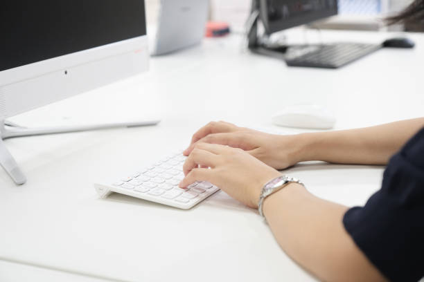 eine japanerin, die in ihrem büro einen computer bedient - verwaltungsangestellter stock-fotos und bilder