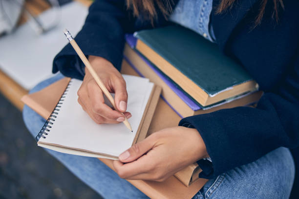 istock Lady in spring clothes holding books on her knees 1253379424
