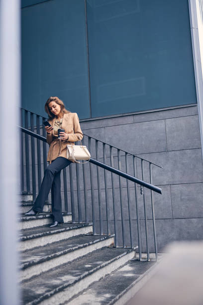 istock Woman with a cellphone standing on the staircase 1253381507