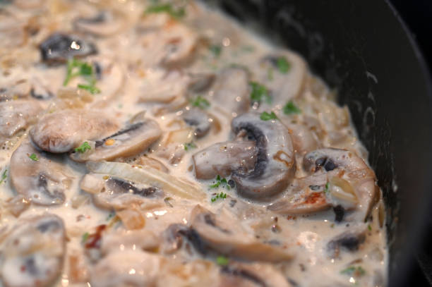 Creamy mushroom Alfredo sauce simmering in a pot.
