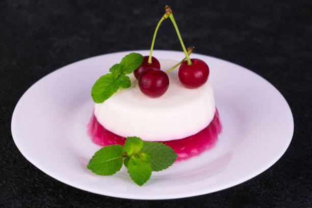 istock Panacotta dessert with cherry jelly on a black background. 1253383352