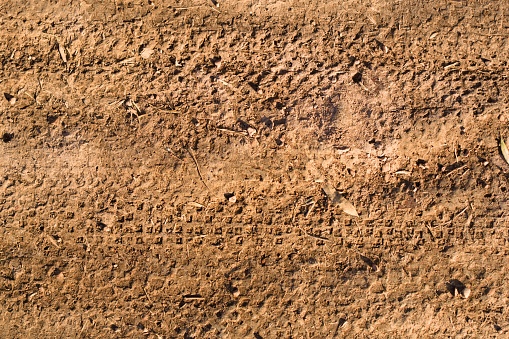 Close-up of a diagonal tire tread pattern from a construction machine in sand on a roadworks site.