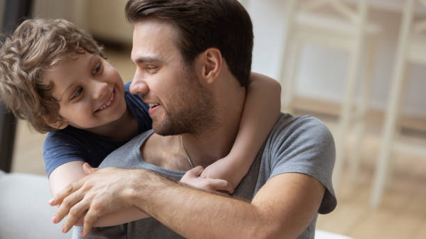 istock Smiling young dad and son hug relaxing at home 1253390168