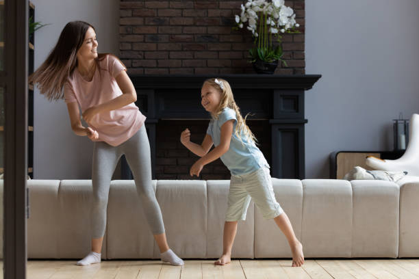 istock Happy mom and daughter dancing together at home 1253390186
