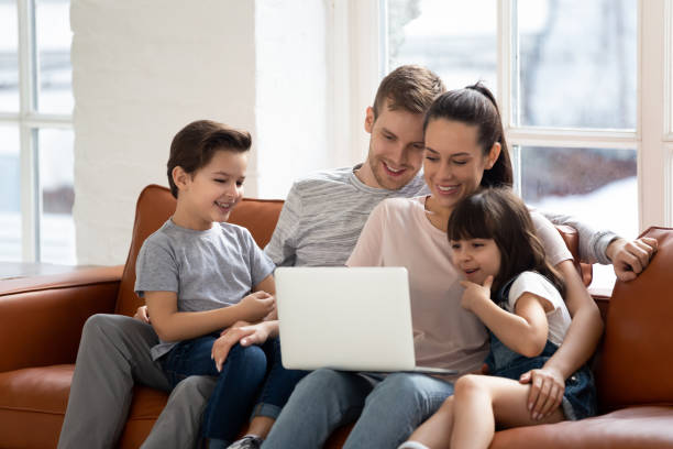 istock Happy parents with little daughter and son using laptop. 1253390266