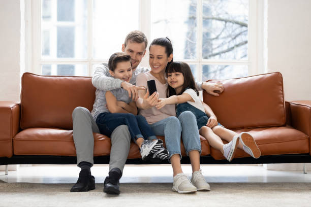 istock Happy family with two children having good time using smartphone. 1253390268