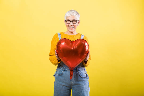 istock Older woman holding a heart shaped balloon 1253390444