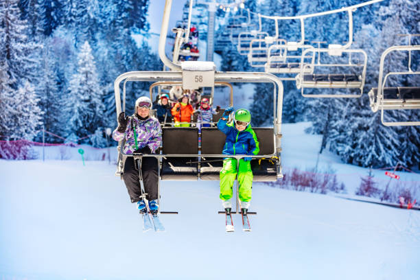 istock Children on ski lift wave hands over snow forest 1253390609