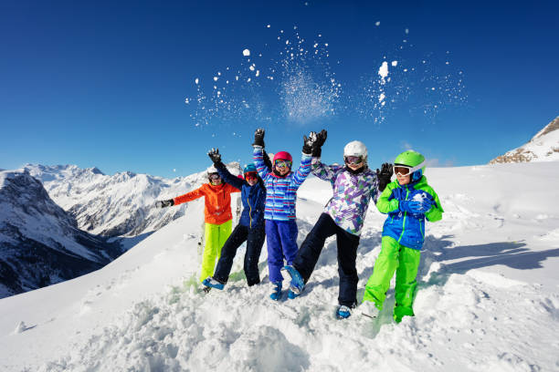 istock Fun ski children group over mountain throw snow up 1253390629
