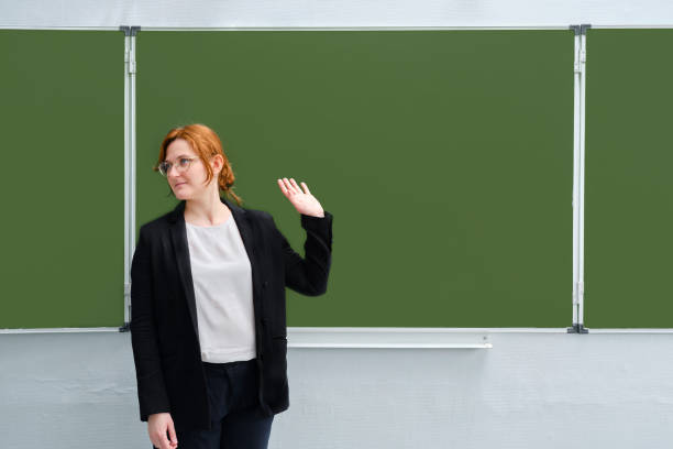 school teacher waves his hand against the blackboard, copy space. the concept of leaving school, completing lessons, or being fired - apple for the teacher imagens e fotografias de stock