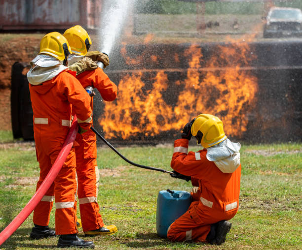 istock Group of firefighter in fire suit using water and chemical foam from fire Extinguisher Hose fight with fire flames inside burning premises. Fireman teamwork spraying high pressure water fight a fire. 1253392122