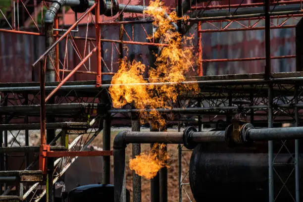 Photo of Fire flames engulfing from gas pipeline leaking. Oil pipeline explosion and billowing fire flames at fuel gas station. Firefighter on duty rescue and industrial safety concept.