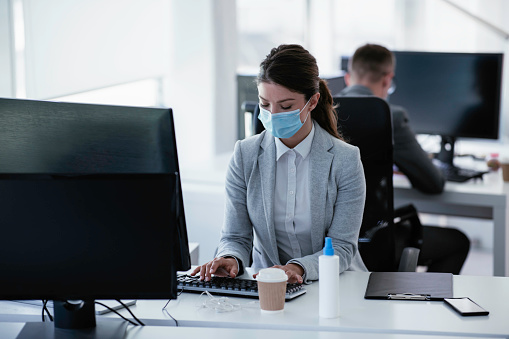 Businesswoman with a medical mask working in the office. Covid-19 concept
