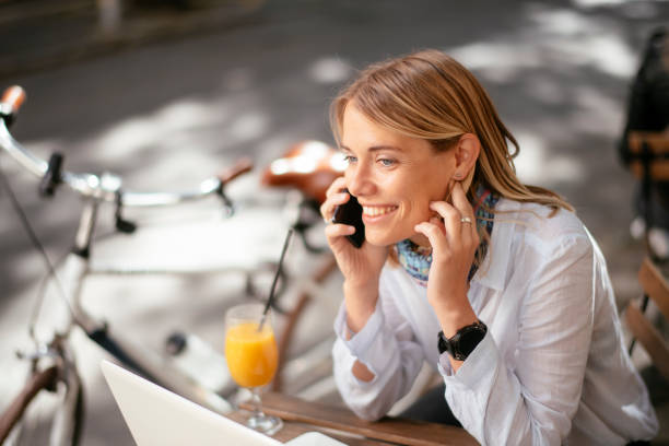 istock Young beautiful woman in cafe talking to the phone while working on computer. 1253395849