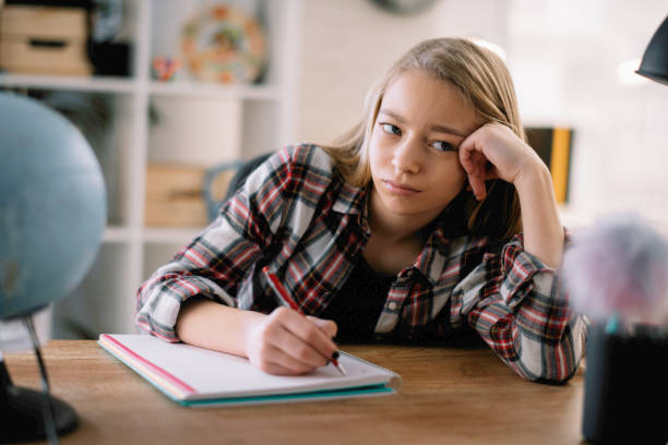 istock Tired little girl doing homework at home. 1253396373