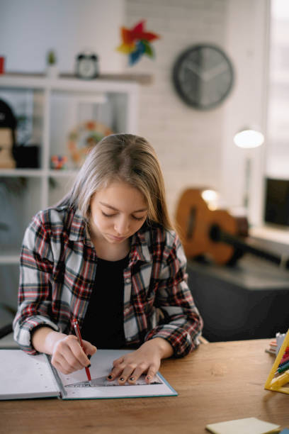 istock Tired little girl doing homework at home. 1253396392