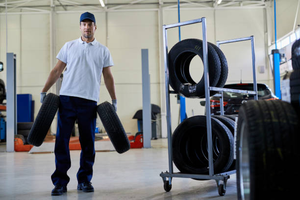 istock Auto repairman carrying car tires while working in a workshop. 1253396643