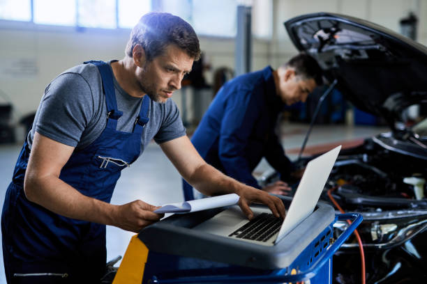 istock Auto repairman using laptop while working with a colleague in a workshop. 1253396803