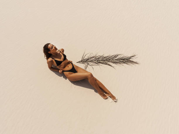 top aerial drone view of woman in swimsuit bikini relaxing and sunbathing on beach - swimwear bikini women fashion model - fotografias e filmes do acervo