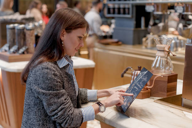 istock Young beautiful girl in a gray coat is studying the menu. 1253402865