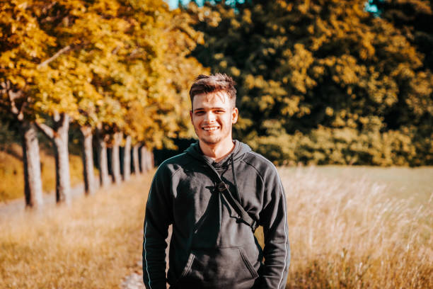 istock Happy smiling young man standing in front of summer field 1253405213