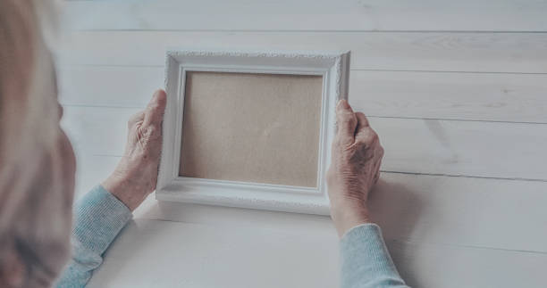 istock Senior wrinkled hands holding white photo frame. 1253407685
