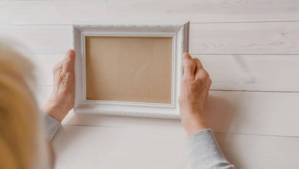 istock Senior wrinkled hands holding white photo frame. 1253407767