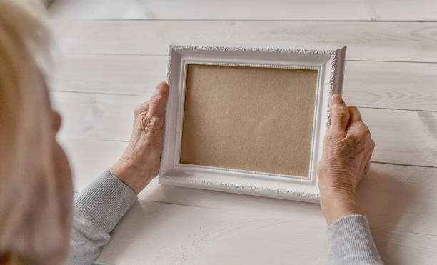 istock Senior wrinkled hands holding white photo frame. 1253407855