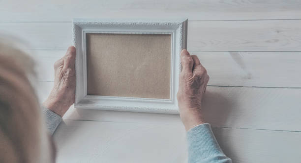 istock Senior wrinkled hands holding white photo frame. 1253407967