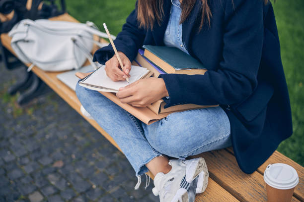 istock Lady in jeans studying outside with cup of coffee 1253410025