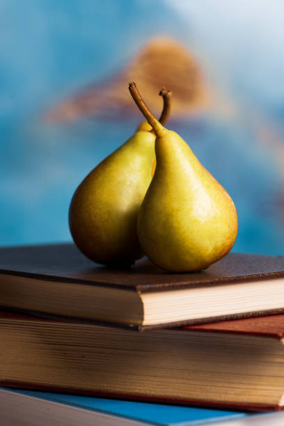 Delicious ripe pear lies next to a stack of books