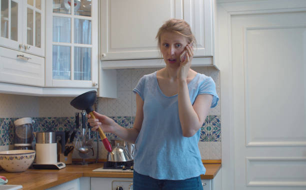donna confusa in cucina con uno stantuffo tra le mani - plunger foto e immagini stock
